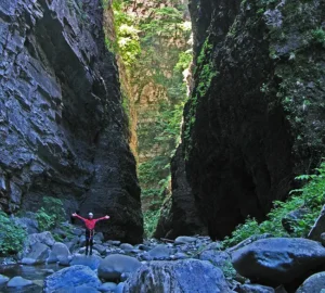 Member of the Apians outdoor adventure team standing inside the vast limestone gorge of Orridi di Botri, surrounded by towering rock walls.